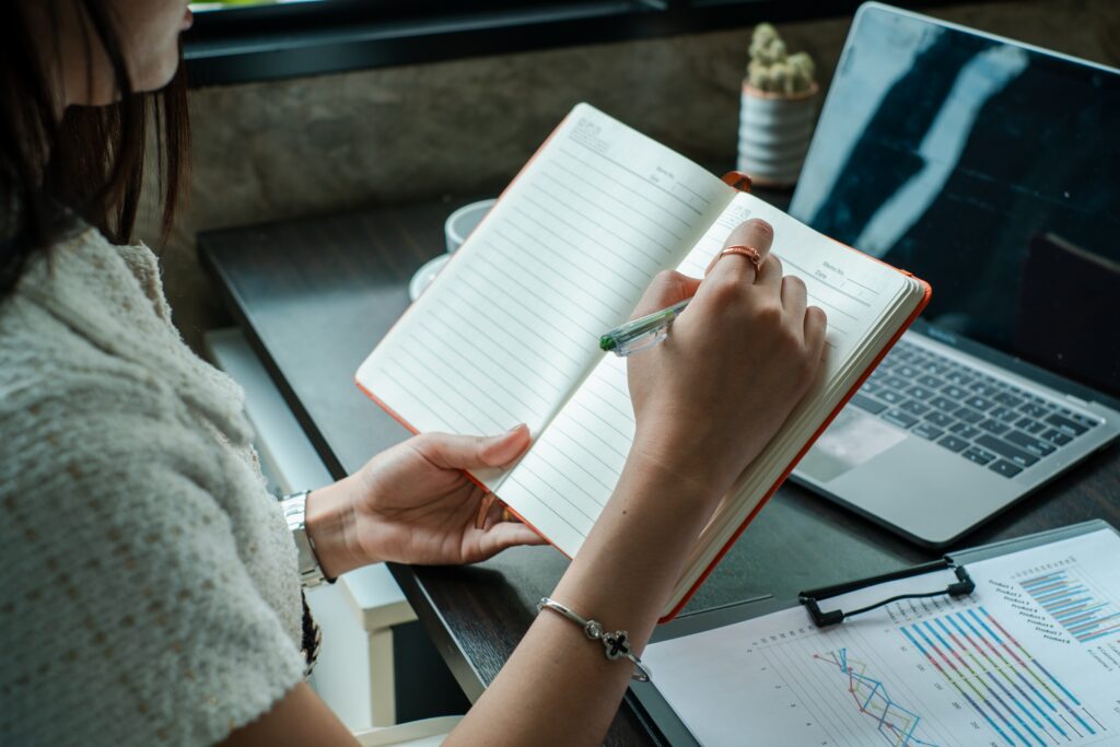 Professional woman taking notes at desk with laptop